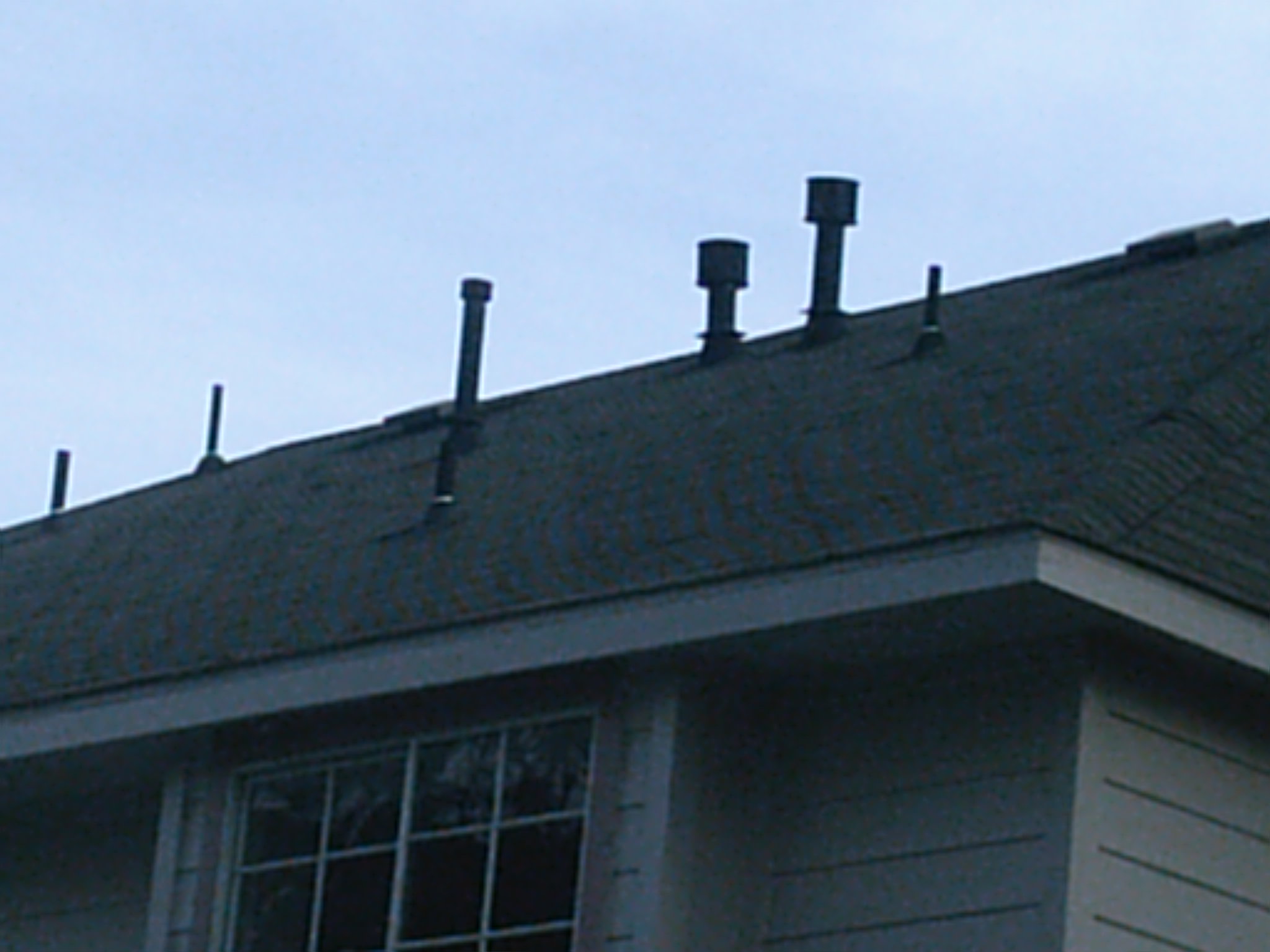 Vent pipe boots installed on a tile roof, multiple pipe penetrations with metal and rubber flashings showing the importance of proper pipe boot specification