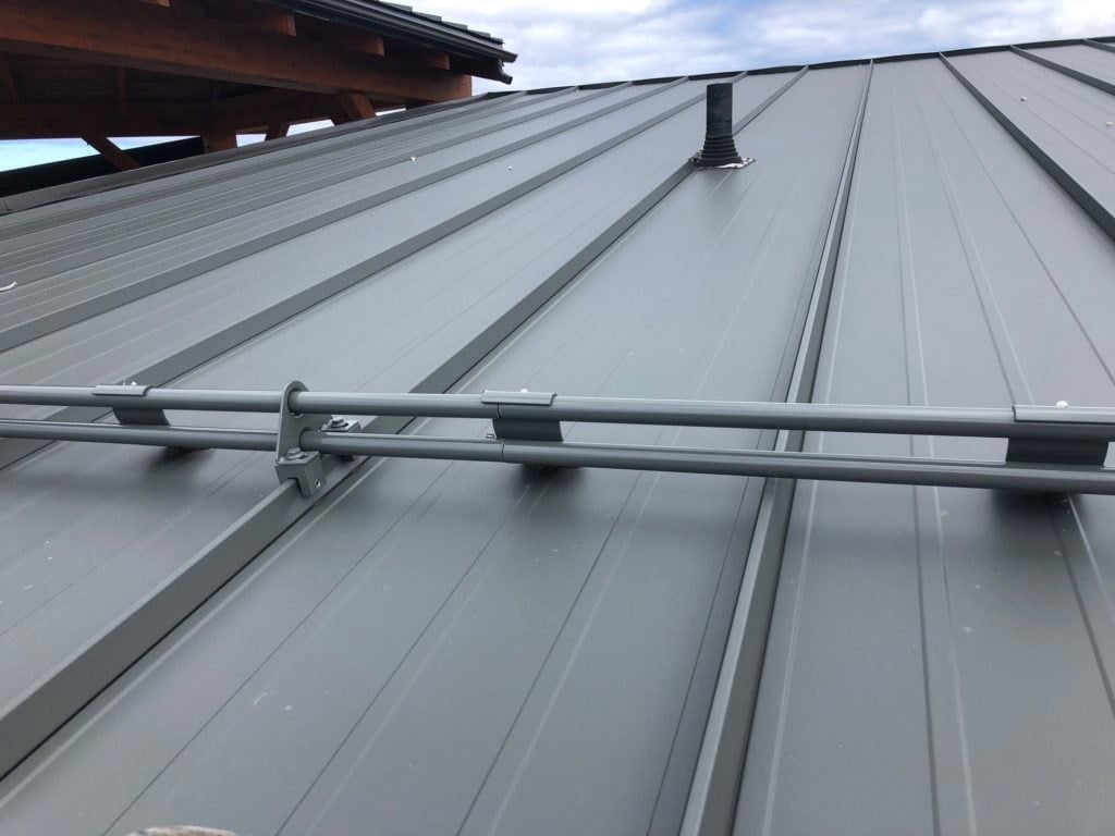 S-5! DualGard snow retention bars installed on a standing seam metal roof, two-pipe aluminum system attached via seam clamps with zero panel penetration
