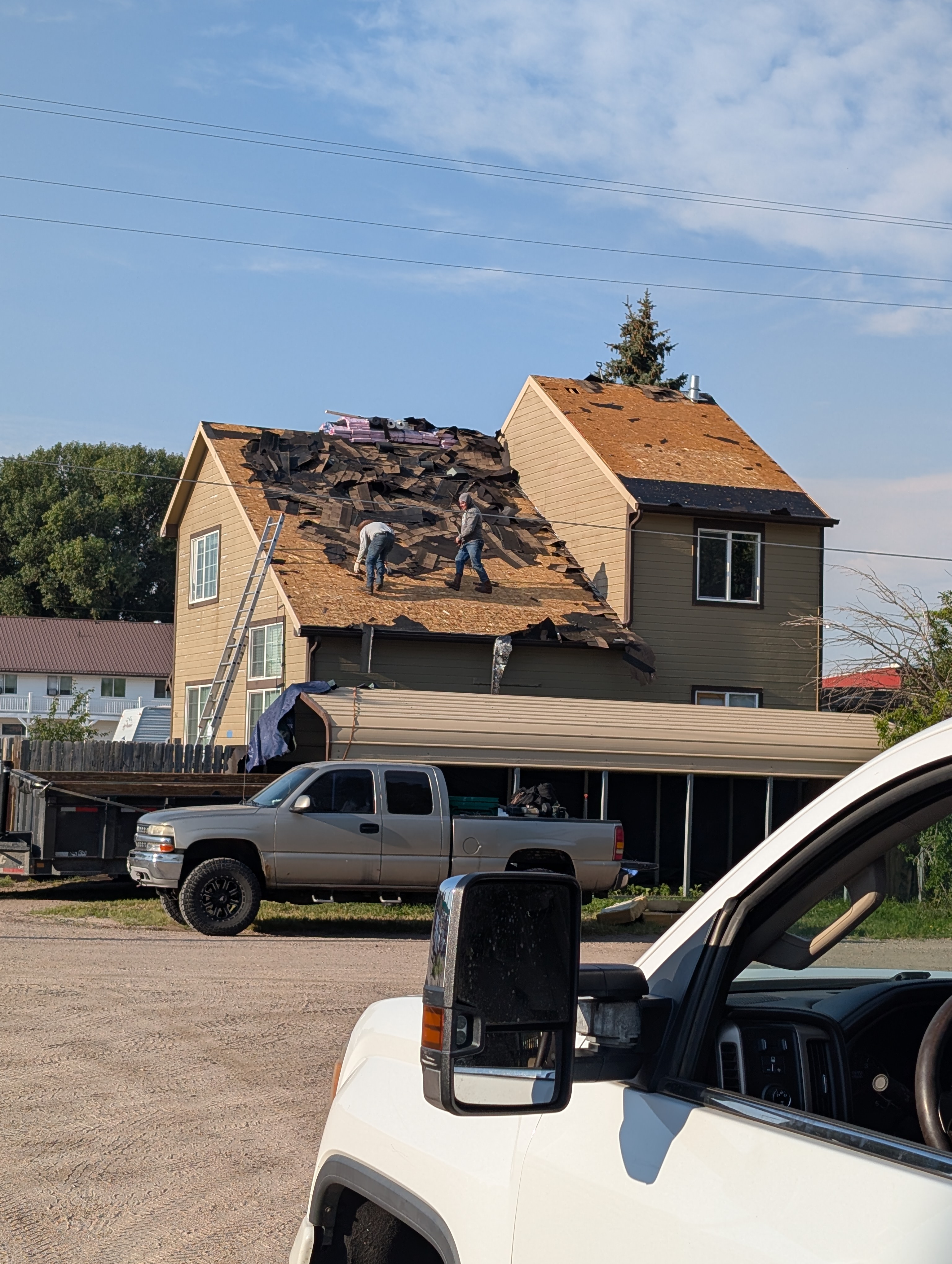 Residential asphalt shingle tear-off with removed shingles on the ground